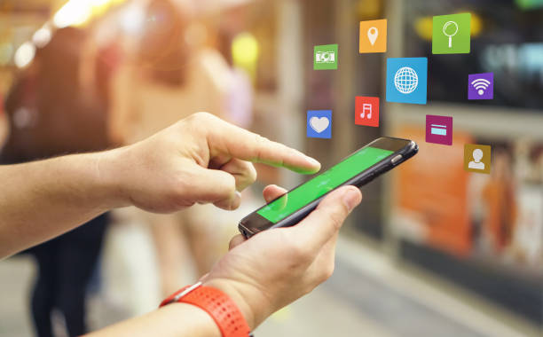 close-up of hand using mobile phone with icons at railroad station - 移动营销新时代 個照片及圖片檔